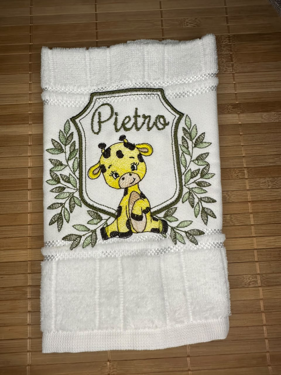 Toalhinha branca com girafa bordada e o nome Pietro